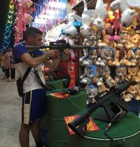 Enfant sur un dtand de tir dans une fête foraine.